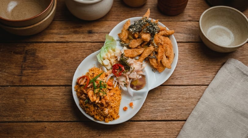 Peruvian seafood platter with arroz con mariscos, ceviche, and fried fish on a wooden table.
